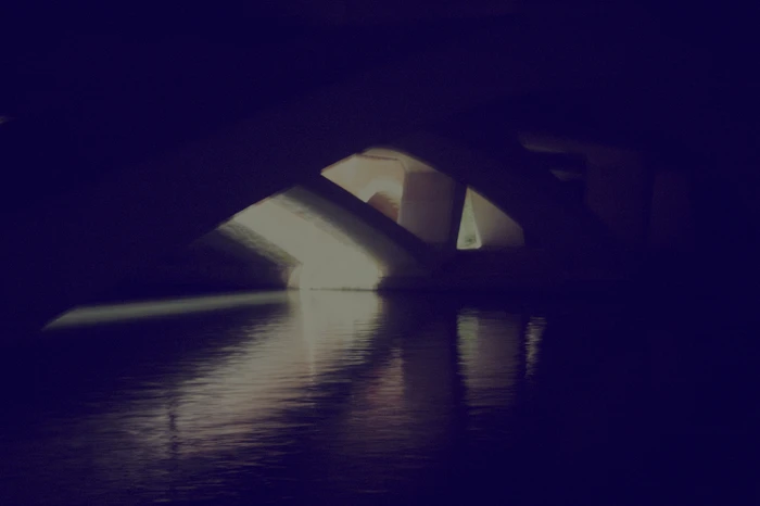 Night view of illuminated bridge arches casting reflections on dark water by photographer Noel Mclaughlin.