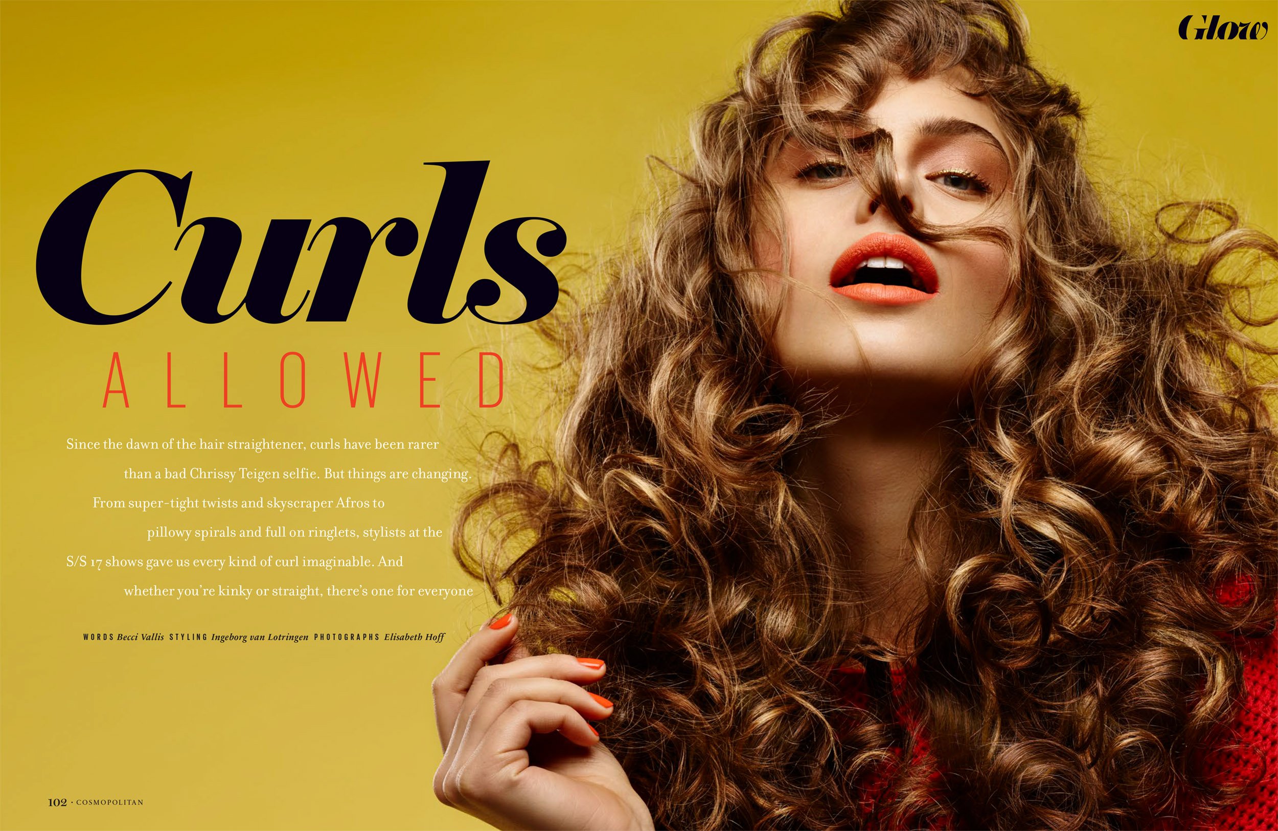 Beauty editorial shot of a woman with curly hair and orange lipstick against a yellow background, showcasing a modern hair style.