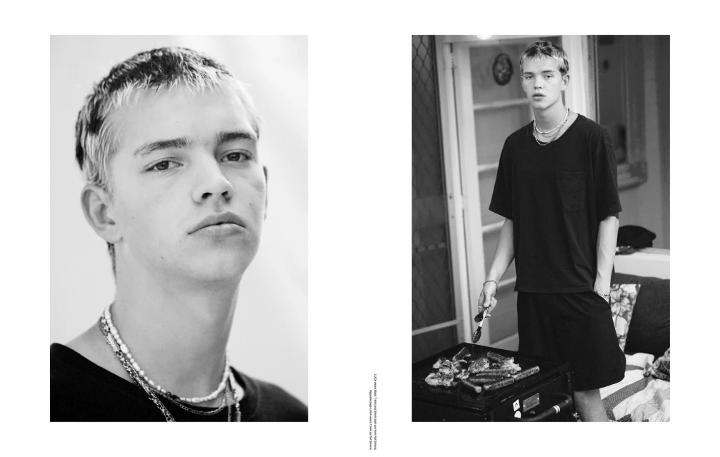 Black and white portrait of a young adult male with blond hair wearing necklaces, and a male cooking at a grill outdoors.
