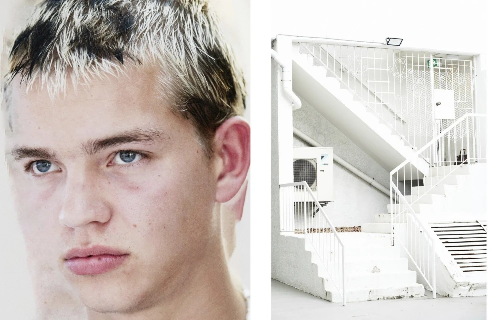 Studio shot featuring a young man with bleached hair in a close-up composition against a white staircase in the backdrop.