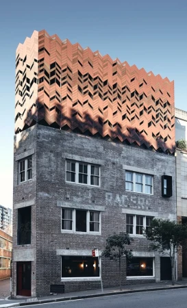 Exterior daytime shot of a multi-story building with brick facade and zigzag patterned upper section, set against a clear blue sky.