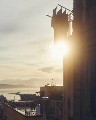 Scenic view of laundry drying on a line outside a building with a city and the sea in the distance during golden hour.