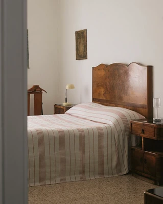 Bedroom interior with a wooden headboard bed, striped bedding, and side tables with lamps, creating a cozy and inviting atmosphere.