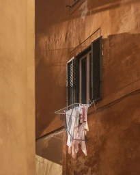 Laundry hanging on a rack outside a window on a warm-toned building facade in Sydney