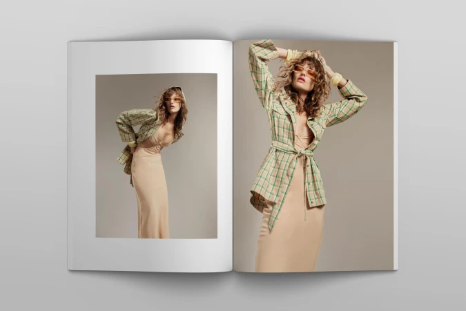 Fashion editorial photograph in an open magazine featuring a woman in a plaid shirt and dress, posing with a neutral background.