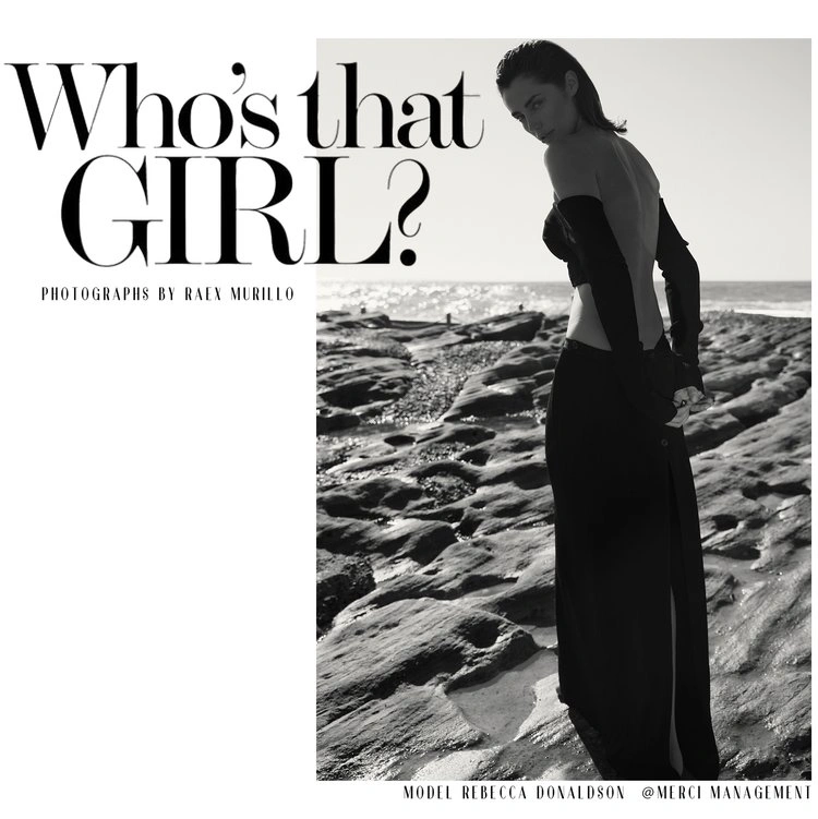 Black and white editorial portrait of a woman in a black off-shoulder dress standing on rocky coastal shore by Raex Murillo