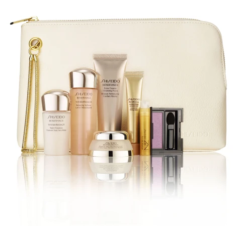 Arrangement of Shiseido Benefiance skincare products including creams, lotions, and eye shadow, presented in front of a white cosmetic bag.