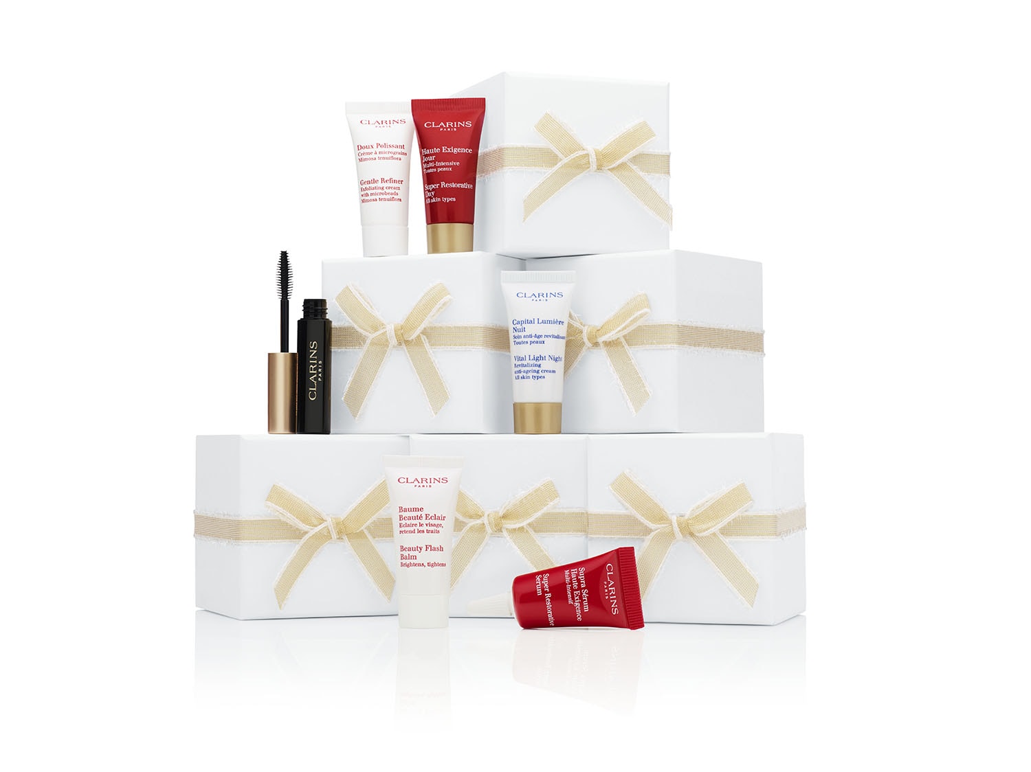 Clarins beauty product collection on stacked gift boxes with ribbons. Skincare, makeup, and cosmetics arranged on white backdrop.