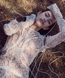 Woman in intricate white lace dress lying on mossy ground, photographed from above by Nicole Bentley in Sydney.