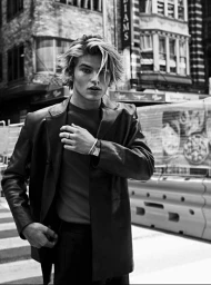 Monochrome portrait of a young male model with tousled blonde-streaked hair wearing a leather blazer outdoors in Sydney.