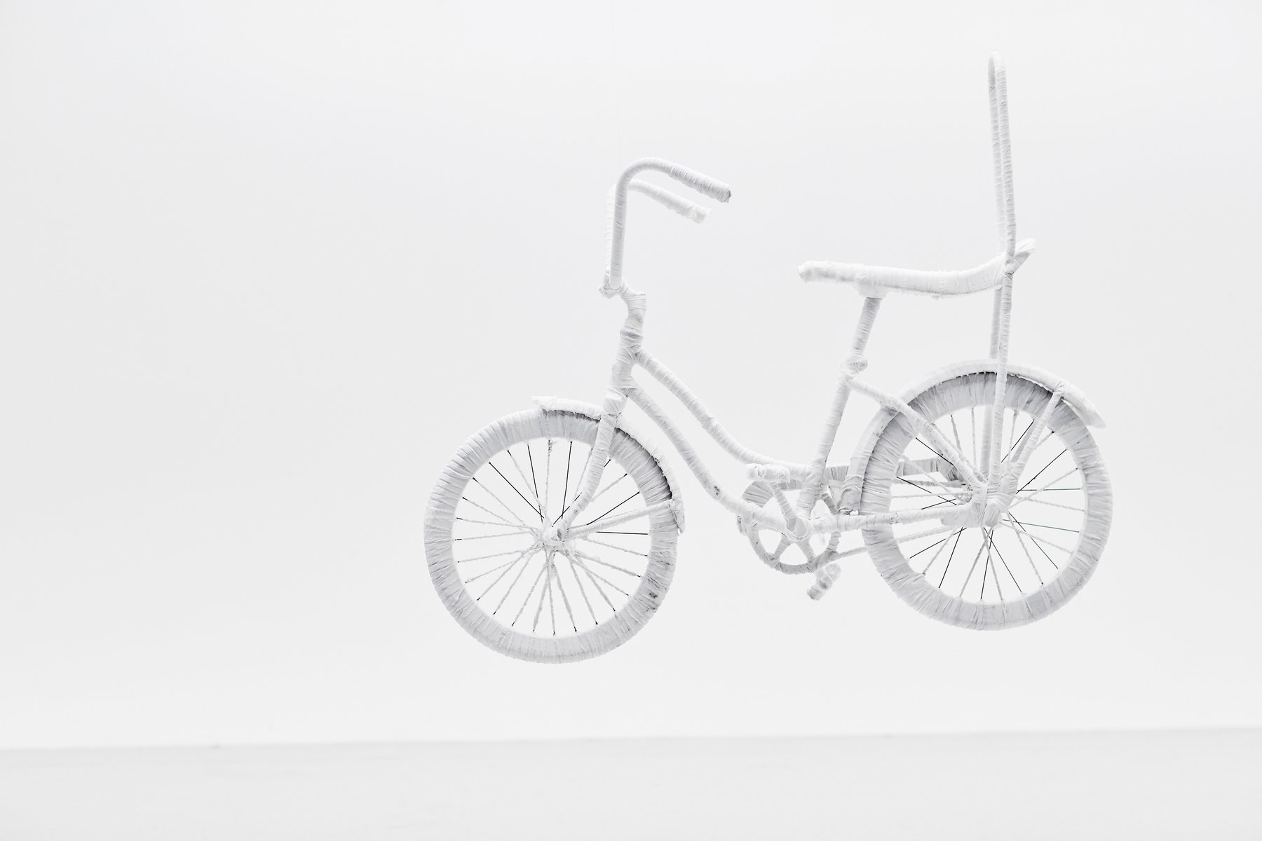 Monochromatic white sculpture of a custom bicycle wrapped entirely in textured white material against a plain white studio background.