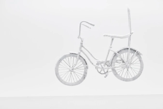 Monochromatic white sculpture of a custom bicycle wrapped entirely in textured white material against a plain white studio background.