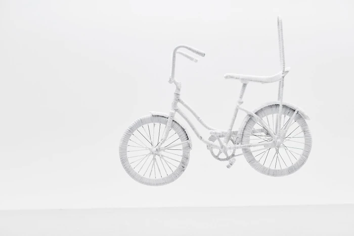 Monochromatic white sculpture of a custom bicycle wrapped entirely in textured white material against a plain white studio background.
