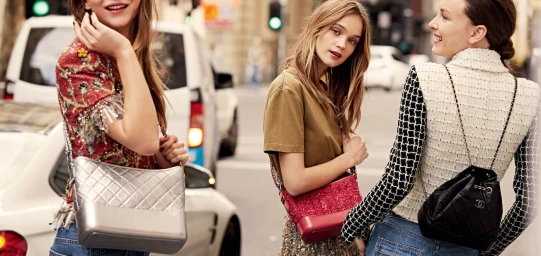 Three female models walking on a city street carrying quilted handbags with chain straps in Sydney
