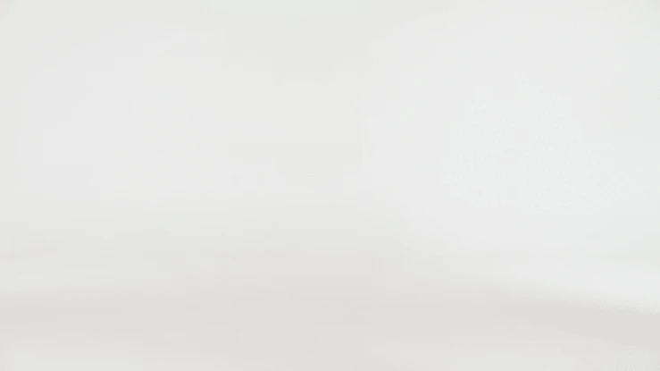 An empty white photo studio backdrop, with a soft graduated gradient, suitable for product photography or portraiture, in a bright setting.