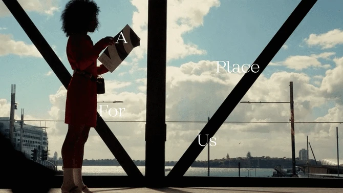 Woman in red dress silhouetted against a window overlooking a cityscape and water, holding a magazine, with text overlay.