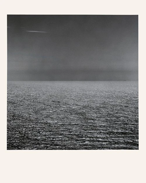Monochrome photograph of an ocean view under an overcast sky, the horizon line splitting the frame into equal parts of sea and sky.