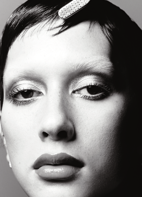 Monochrome close-up shot of a young adult female's face with glossy lips, wearing a hair clip, and soft lighting.