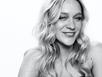 Black and white portrait of a smiling blonde woman with wavy hair against a plain light background