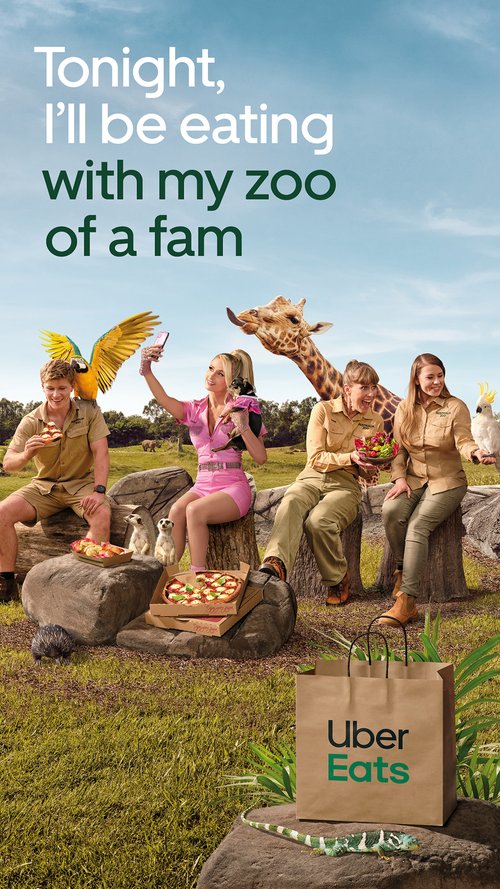 Whimsical ad with four people and various animals around food and an Uber Eats bag in a grassy field on a sunny day.