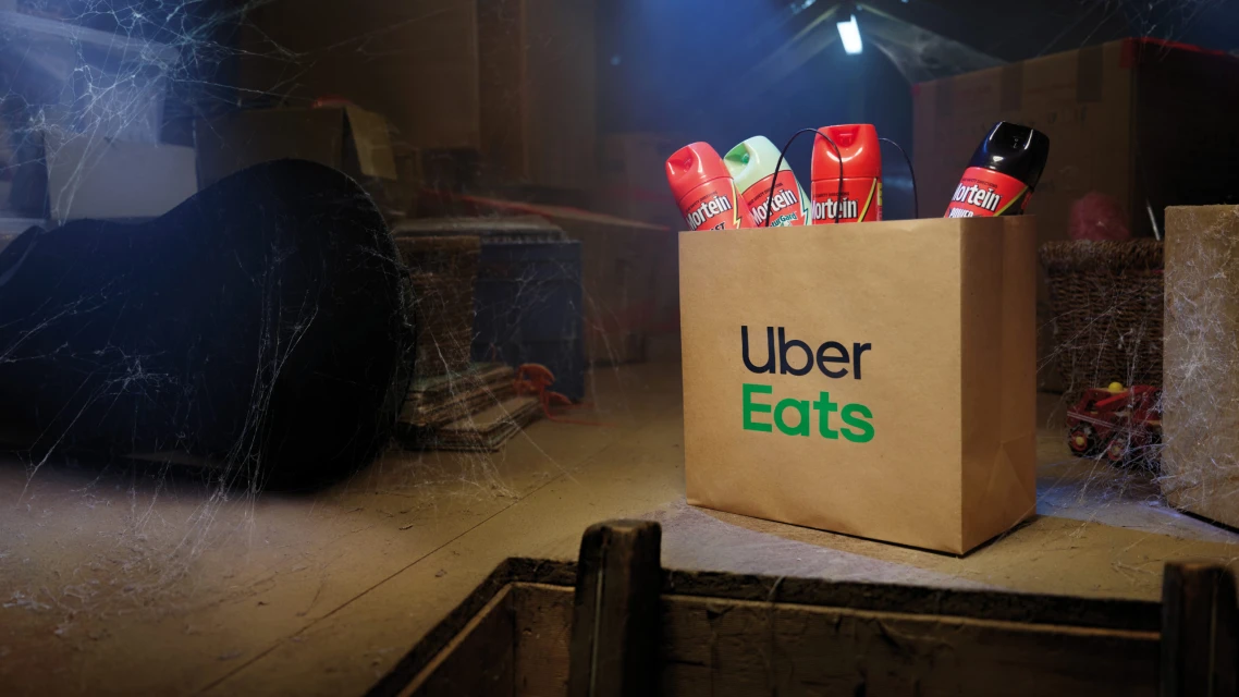 Uber Eats delivery in dark, dusty attic with Morten bug spray cans. Halloween ad, pest control, and home delivery concept.