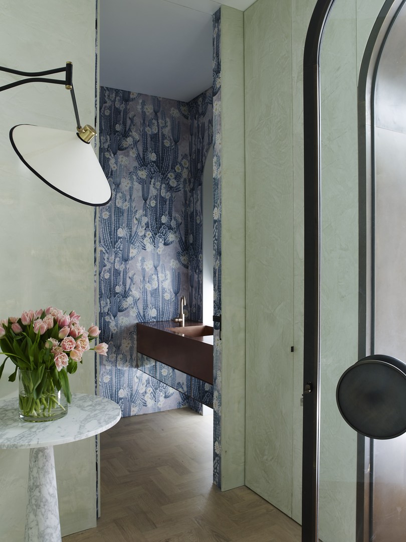 Elegant bathroom interior featuring floral wallpaper, marble side table with pink roses, and a minimalist vanity with stylish fixtures.