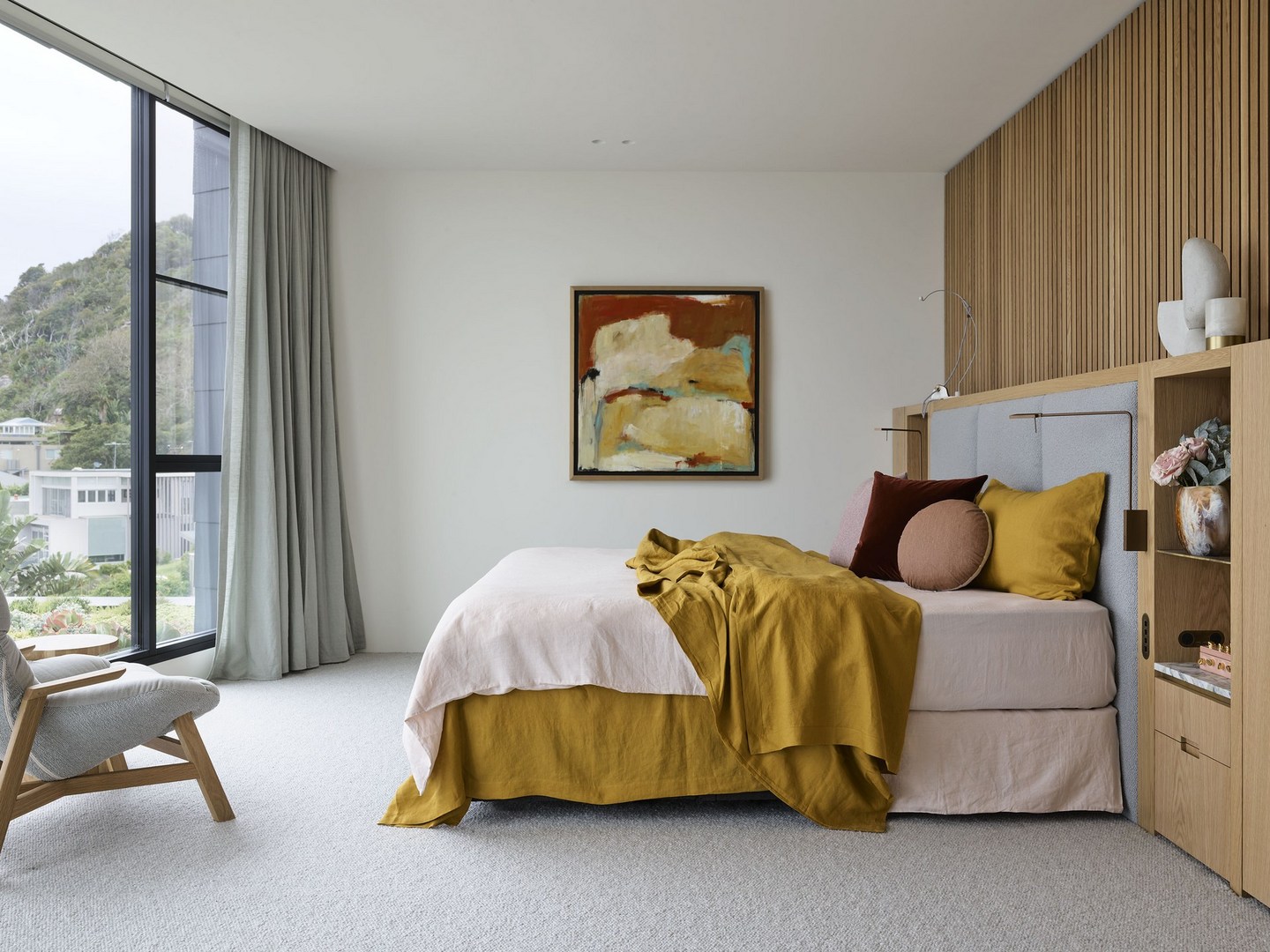 Bedroom interior featuring a platform bed with yellow and pink linens, a wooden accent wall, and a large window with a view.