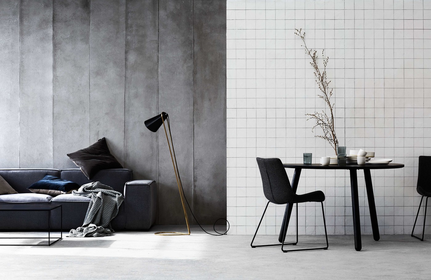 Living room interior with grey sofa, floor lamp, round dining table and chairs in a minimalist neutral colour scheme.