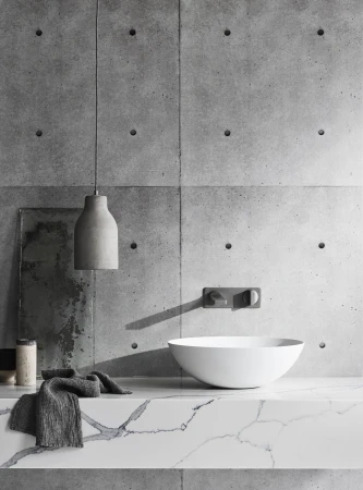 Bathroom interior featuring a white vessel sink, concrete accent wall, gray pendant light, and marble countertop for an elegant look.