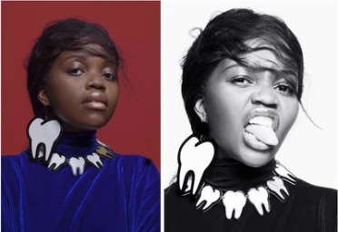 Portrait of a Black woman wearing a large tooth-shaped statement necklace and blue top against a dark red backdrop