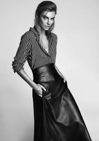 Monochrome portrait of a woman wearing a striped shirt and a long dark leather skirt in a studio setting