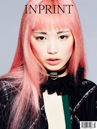 Magazine cover featuring a young Asian woman with pink hair, wearing a black choker and a patterned jacket, against a gray backdrop.