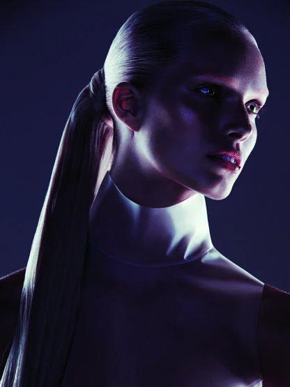 Close-up studio portrait of a sleek adult female with light skin, glossy makeup, a high ponytail, and a modern white collar.