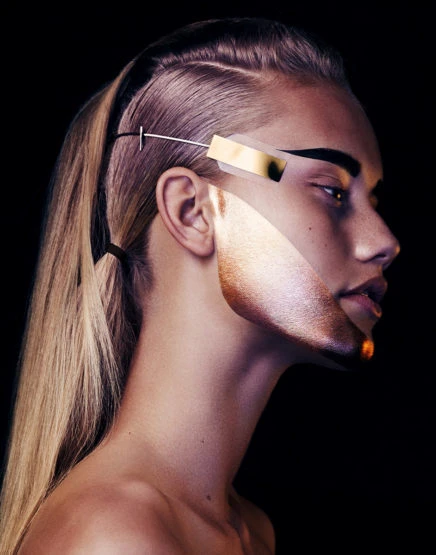 Artistic portrait of a blond woman with a modern hair accessory, featuring creative face makeup, a dark background, and high-fashion aesthetic.