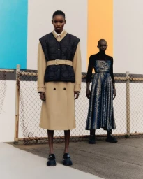 Two black female models posing outdoors against a chain-link fence with color panels, styled by make-up artist Claire Thomson in Sydney
