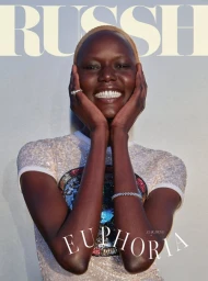 Portrait of a smiling black woman with short blonde hair wearing a sequined top with her hands framing her face