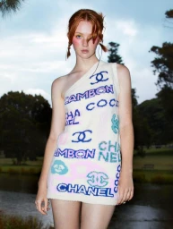 Red-haired female model wearing patterned white knit dress with colorful typography and logo prints outdoors in Sydney.