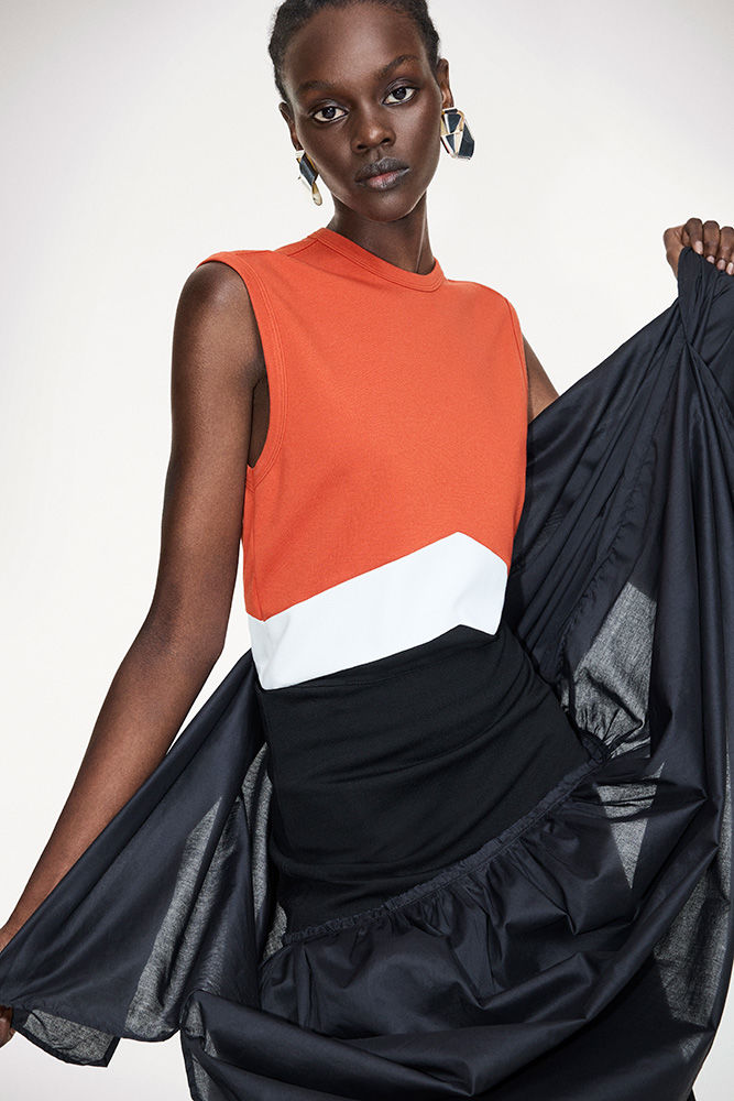 Fashion model in a sleeveless color-block top with a black skirt featuring a dramatic ruffle posing in a bright photo studio.