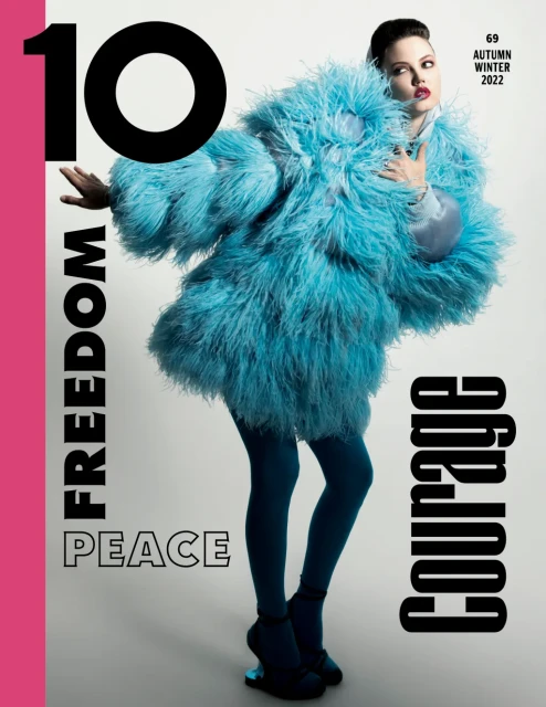 Magazine cover featuring a woman in a blue, feathered coat, blue tights, and platform shoes, with large text reading 'FREEDOM,' 'PEACE,' 'COURAGE.'
