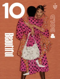 Two models embracing against an orange textured backdrop, featuring bold polka dot and floral print fashion styling.