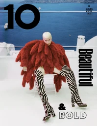 Model with platinum blonde hair wearing a red textured jacket and zebra print boots seated on a rooftop