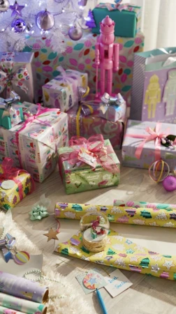 Festive holiday scene with wrapped presents, Christmas tree, wrapping paper, bows, and a snow globe creates a joyful ambiance.