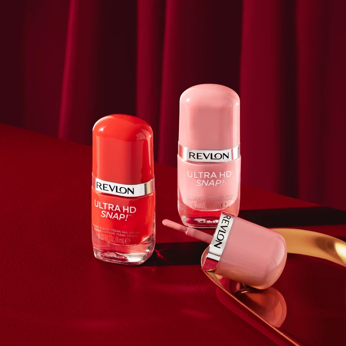 Three Revlon Ultra HD Snap nail polish bottles in red and pink shades displayed on a reflective red surface