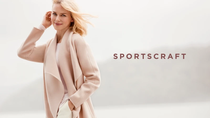 Naomi Watts in a cream coat against an outdoor background, directed by Justin Woo