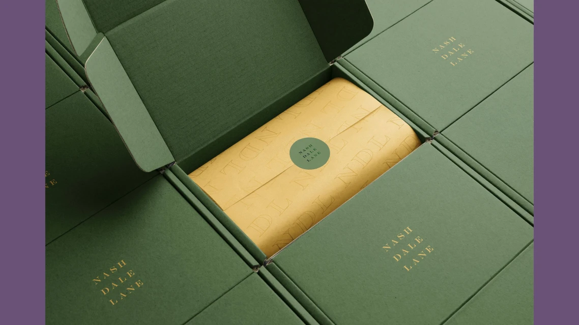 Overhead shot of green boxes with a cream colored package inside, surrounded by more unopened boxes and labels reading Nash Dale Lane.