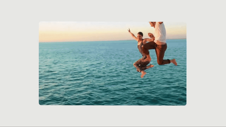 Two people jumping mid-air above the ocean at sunset with clear horizon line.