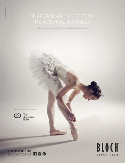 Ballet dancer in white tutu tying pointe shoe, photographed in a photo studio for an Australian Ballet promotional advertisement.