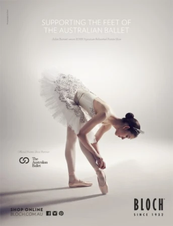 Ballet dancer in white tutu tying pointe shoe, photographed in a photo studio for an Australian Ballet promotional advertisement.