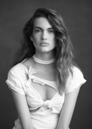 Portrait of a woman wearing a white cutout top with tied details, photographed by Liz Ham in Sydney.