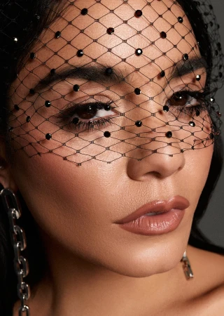 Close-up portrait of Vanessa Hudgens wearing a black embellished net veil over her face by photographer Adrian Mesko.
